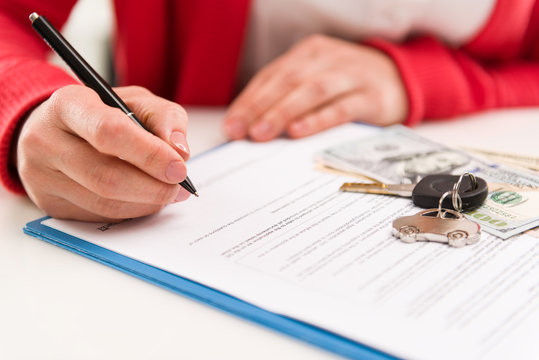 Woman auto dealer signing rental contract in the office