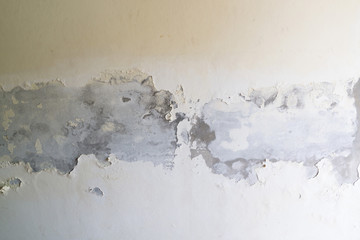 Paint peeling off the white concrete wall