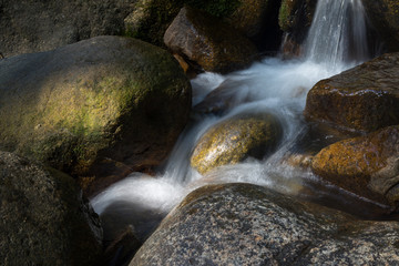 Naklejka na ściany i meble Water flowing and falling off large rocks