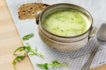 cream soup from arugula  in a rustic bowl, some leaves, spoon an
