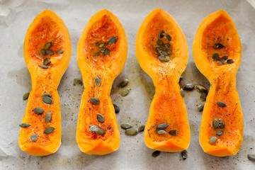 Four butternut squash pieces with pumpkin seeds on white paper