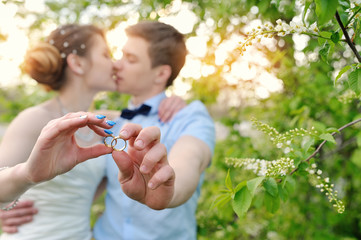 Bride and groom holding rings and kiss