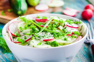 salad of fresh organic radish and cucumber in white bowl closeup