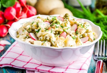 potato salad with fresh radishes and dill in a white bowl