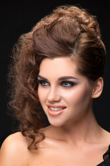 Portrait of a young brunette woman hairstyle curls on a black ba