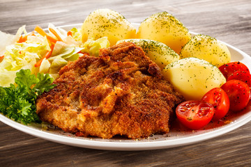 Fried pork chop, boiled potatoes and vegetable salad 