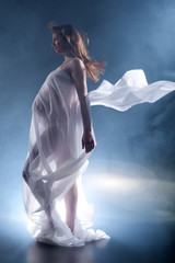 Frau mit Babybauch und fliegenden Tuch im Wind und Nebel wie ein Engel Porträt