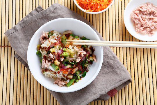 Rice noodles with tuna, peas and onions in a white bowl