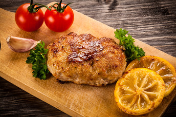 Fried chops and vegetables on cutting board 