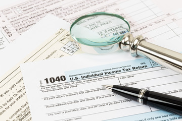 Obraz premium Tax form with pen and magnifying glass taxation concept