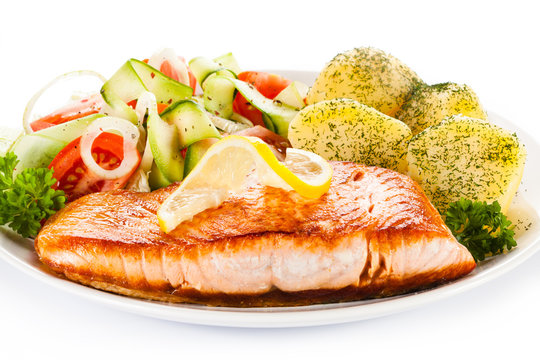 Fried salmon and vegetables on white background