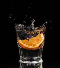 Slice of lemon splashing into a glass of water 