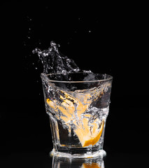 Slice of lemon splashing into a glass of water 