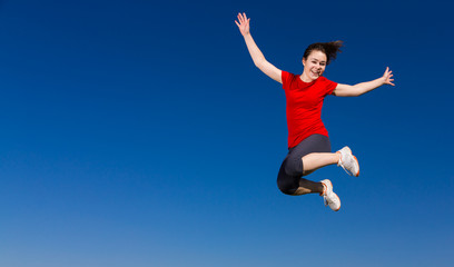 Fototapeta na wymiar Teenage girl jumping, running outdoor against blue sky