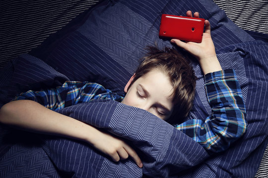 enfant garçon au lit avec smartphone