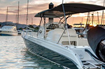 Fototapeta premium Small motorboat docking at the marina at sunset time