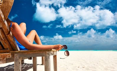 Woman at beach holding sunglasses