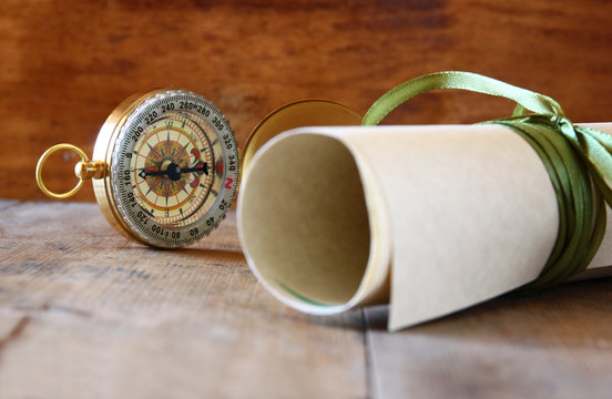old parchment and antique compass on wooden table