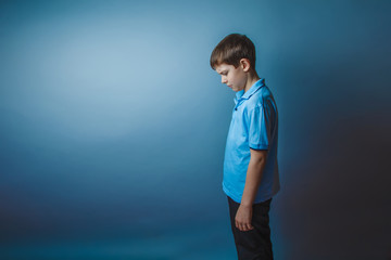 teenager boy Brown European appearance in a blue shirt stands si