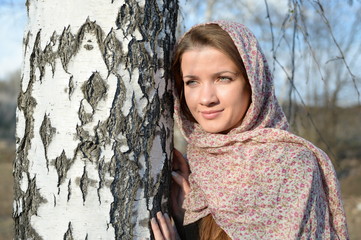 Russian girl in a scarf in a birch forest close up  