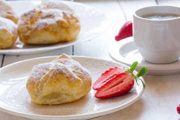 Fluffy bun of puff pastry with strawberry filling and coffee