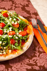 Pizza with rucola and cherry tomatoes on a teble of italian rest