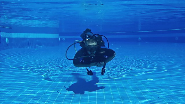 Male Scuba diver swimming underwater in a swimming pool