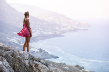 Obraz premium Young woman standing on rock and enjoying beautiful view