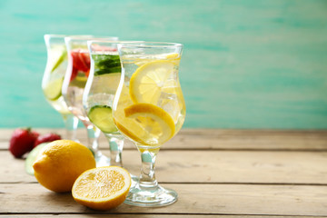 Glasses of different home made freshness healthy vitamin-fortified water on wooden table