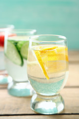 Glasses of different home made freshness healthy vitamin-fortified water on wooden table