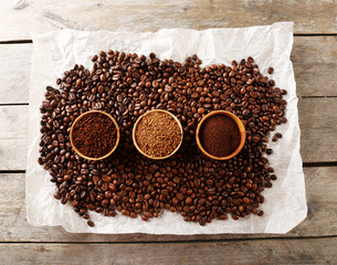 Coffee beans on crumpled parchment on wooden table, top view