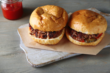 Tasty sandwiches on cutting board, on color wooden background. Unhealthy food concept
