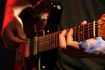 Fototapeta premium Young man playing on electric guitar close up