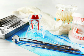 White fake teeth, prosthesis and dental instruments on table background