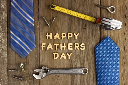 Happy Fathers Day on a wood background with tools and ties frame