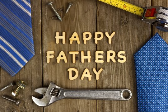 Happy Fathers Day on a wood background with tools and ties frame