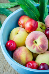 Juicy peaches and apricots in wooden bowl