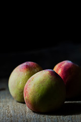 Juicy peaches in old wooden tray on black background