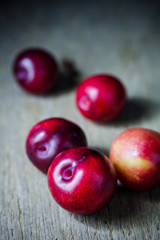 Juicy plums in old wooden tray on black background