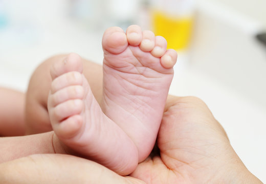 Baby Feet in Mother Hands. New Born Kid Foot