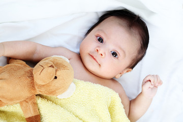 Cute baby boy happy with yellow blanket and doll bear 