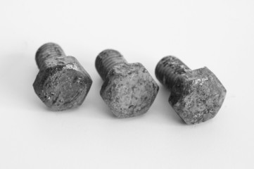 Tres tornillos oxidados sobre fondo blanco