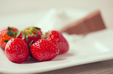 Fresh strawberries, chocolate and whipped cream on a plate