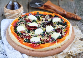 Vegetarian pizza with dried tomatoes, spinach,  cheese. 