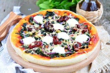Vegetarian pizza with dried tomatoes, spinach,  cheese. 
