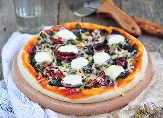 Vegetarian pizza with dried tomatoes, spinach,  cheese. 