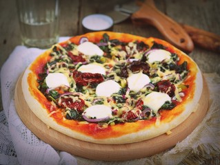 Vegetarian pizza with dried tomatoes, spinach,  cheese. 