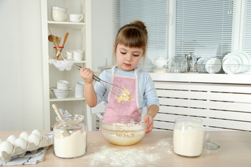 Little girl preparing cookies in kitchen at home