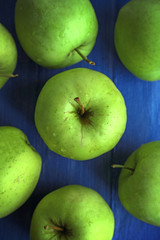 Green apples on color wooden table, closeup