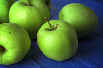 Green apples on color wooden table, closeup